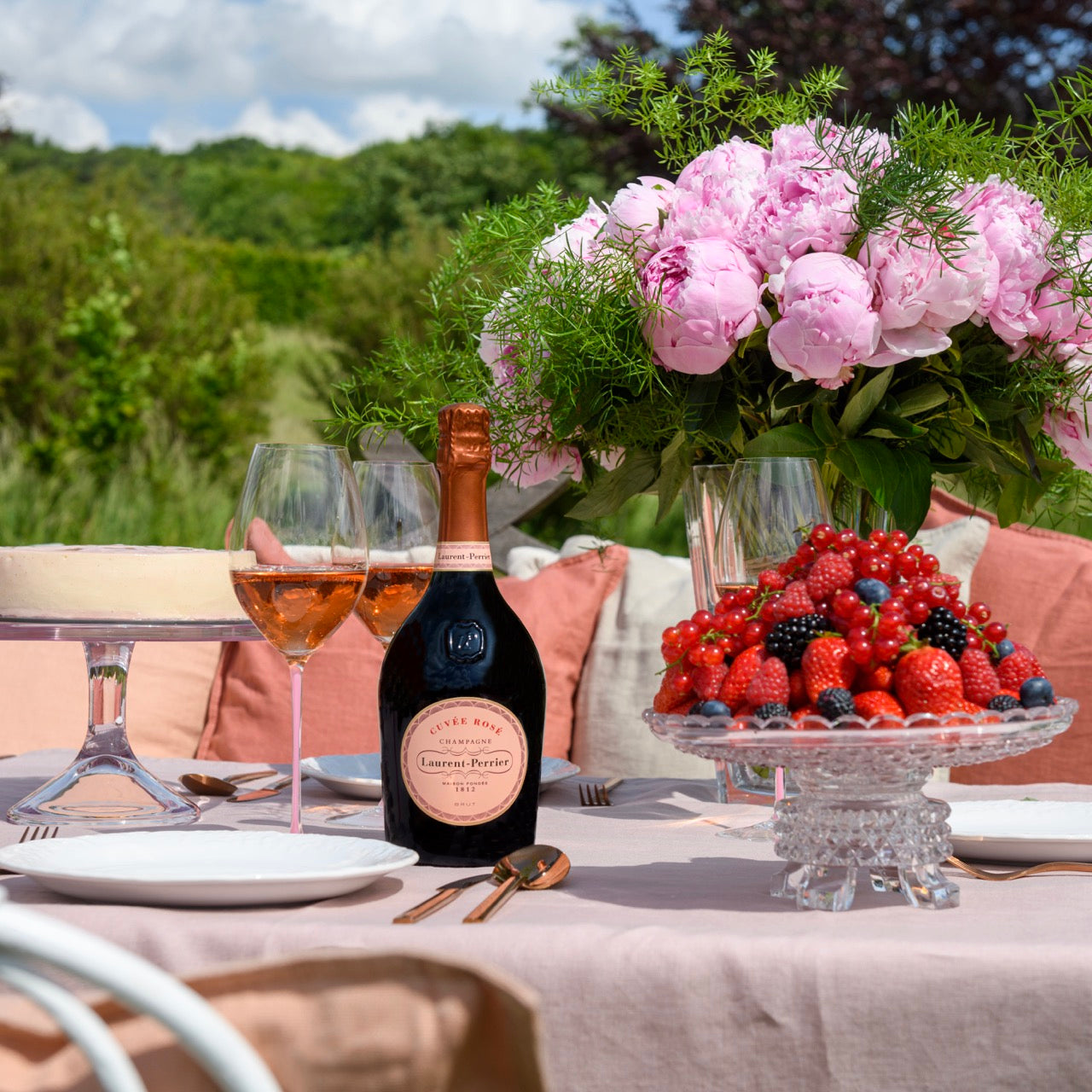 Laurent-Perrier Cuvee Rose on a summer table with peonies and a bowl of berries